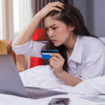 Stressad kvinna som använder bärbar dator för onlineshopping